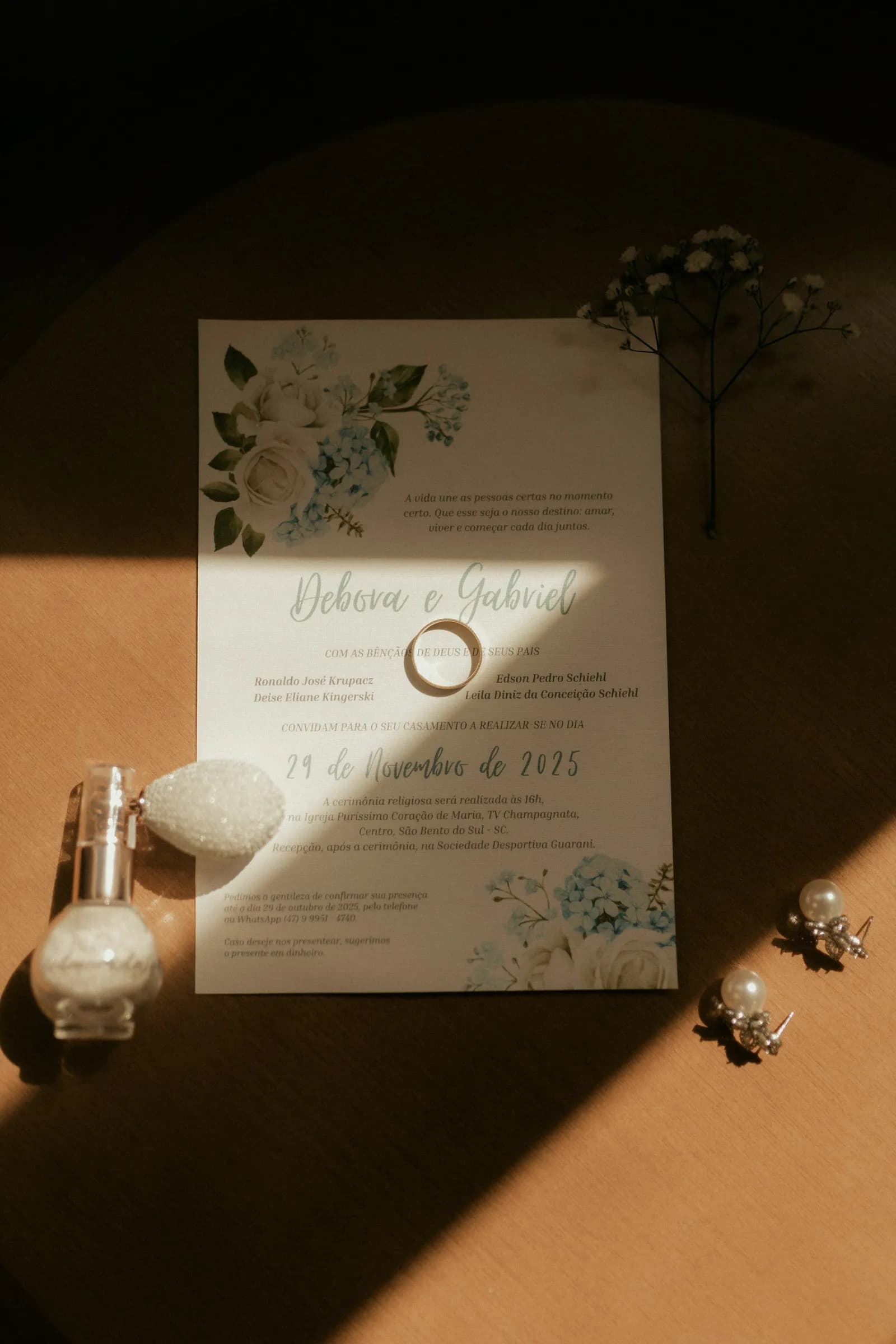 Convite de casamento sob a luz do sol, ao lado de alianças e joias