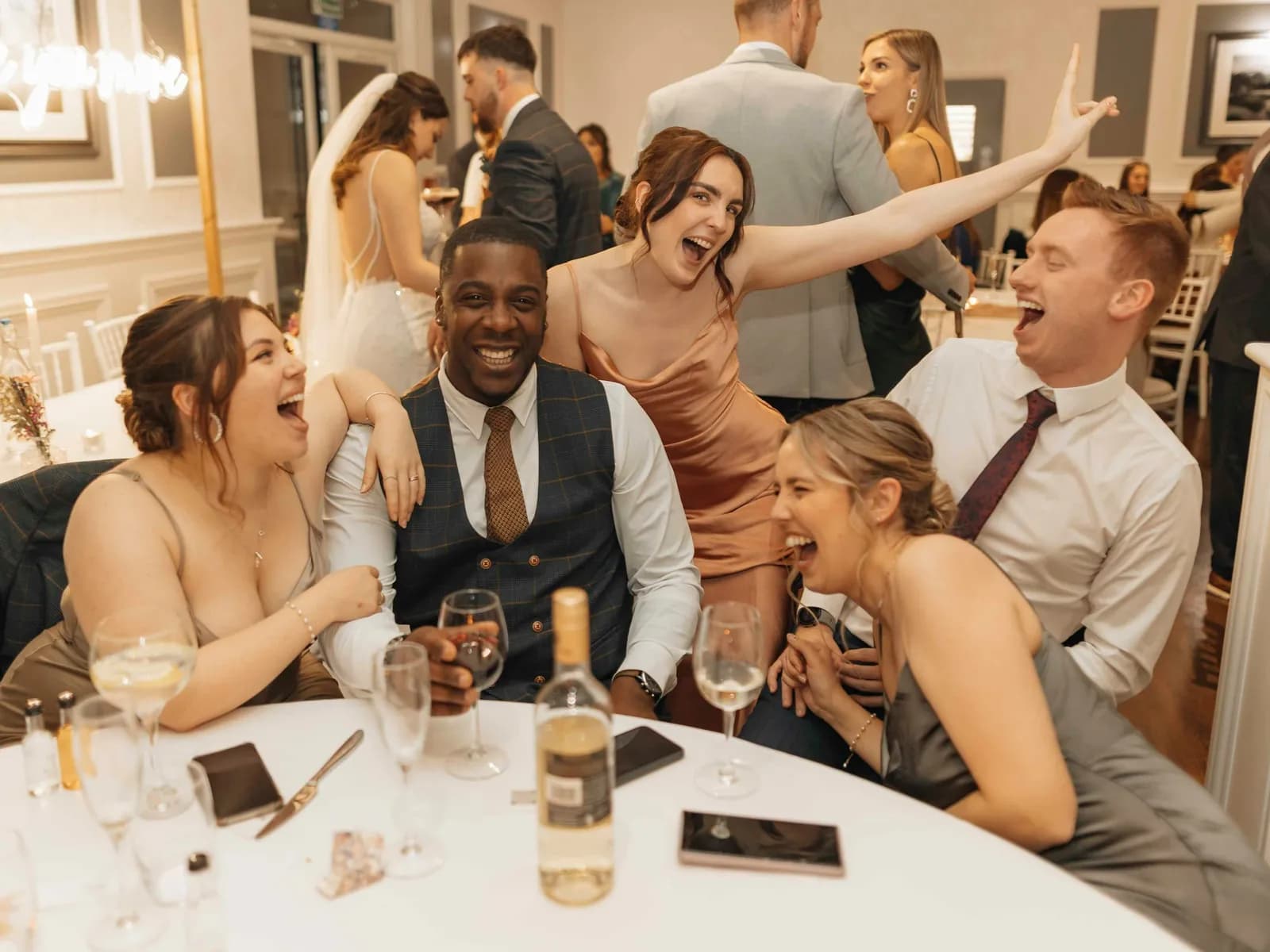 Convidados rindo em volta de uma mesa de festa